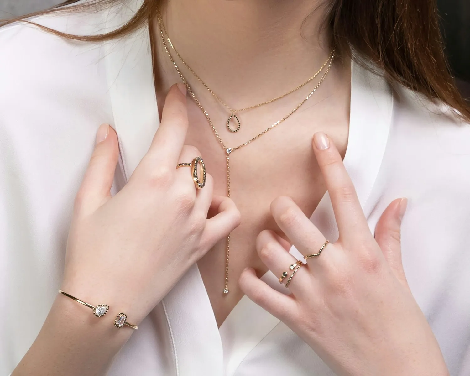 A woman wearing layered gold necklaces and rings